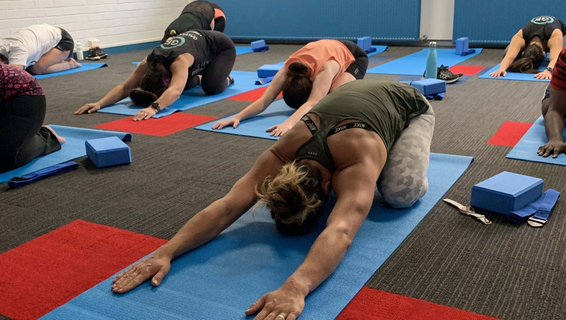 A group of people are doing yoga on mats in a gym.