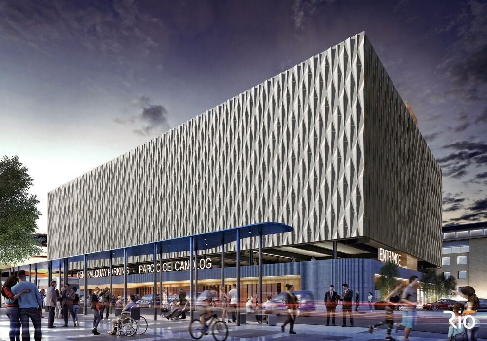 Modern building with textured facade above a transit hub, people milling about.