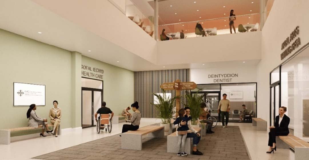 Hospital lobby with waiting area. People sit on benches, near offices, in a modern, light-filled space.