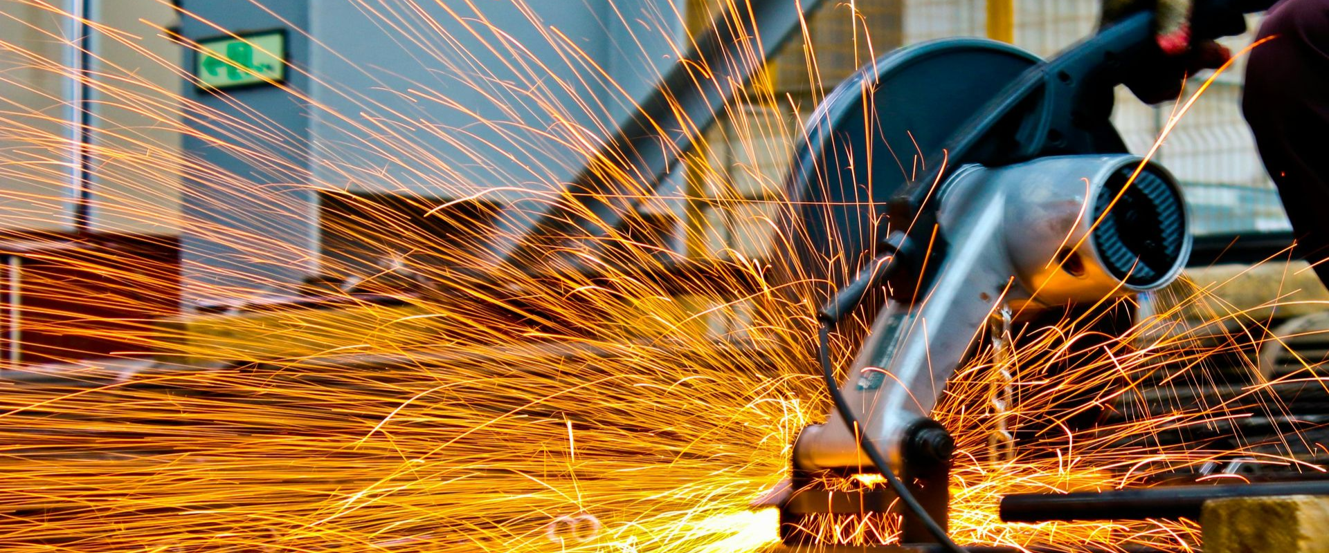 Sparks flying from a metal saw cutting through a metal rod.