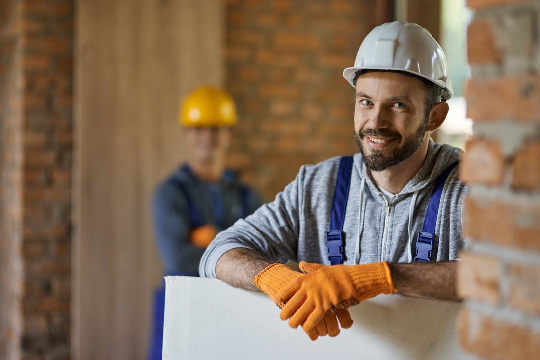 a construction worker wearing a hard hat and gloves is leaning against a wall