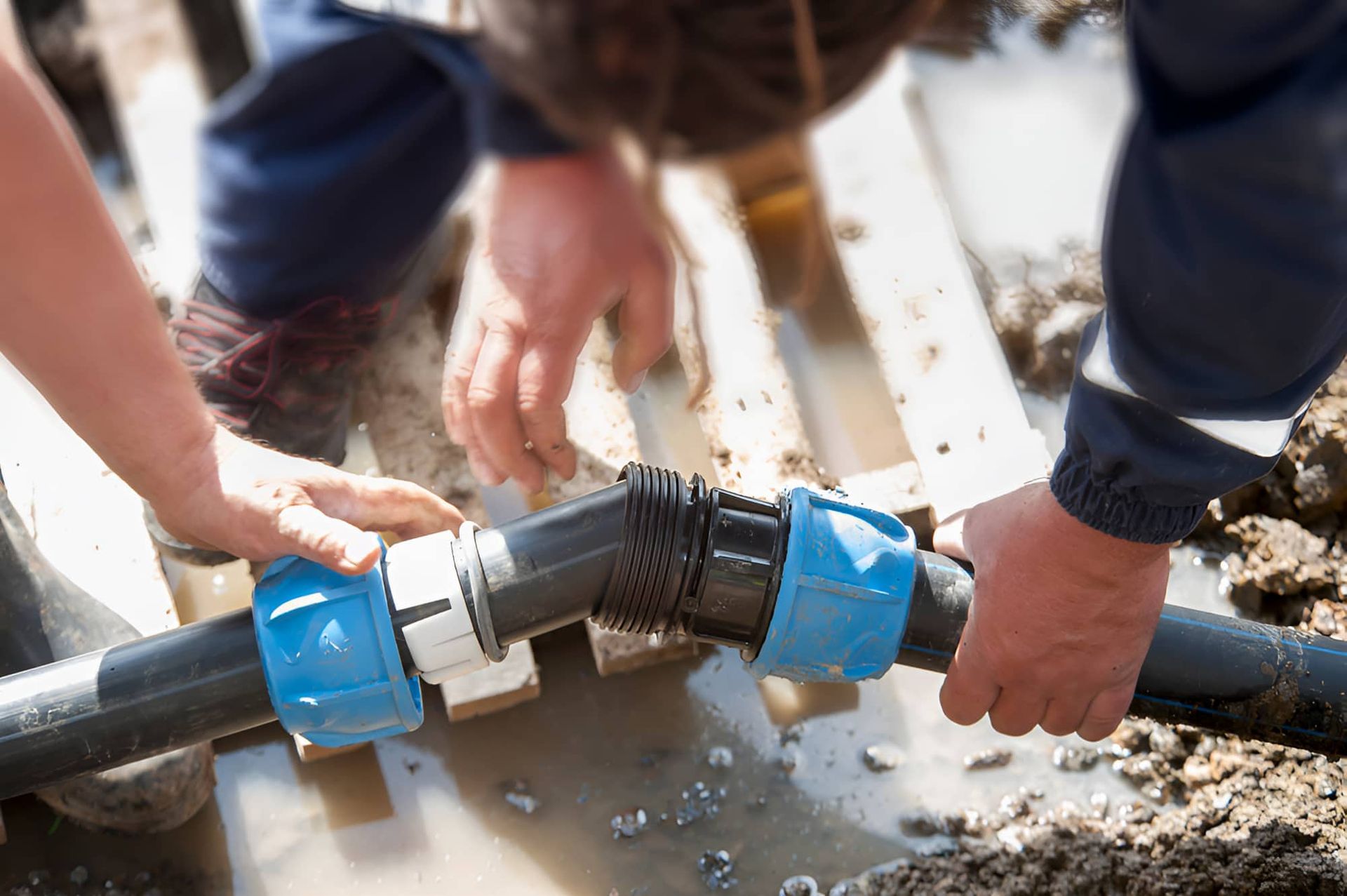 A Man Is Fixing A Pipe In A Puddle Of Water — GPS Plumbing, Drainage & Gasfitting In Dubbo, NSW