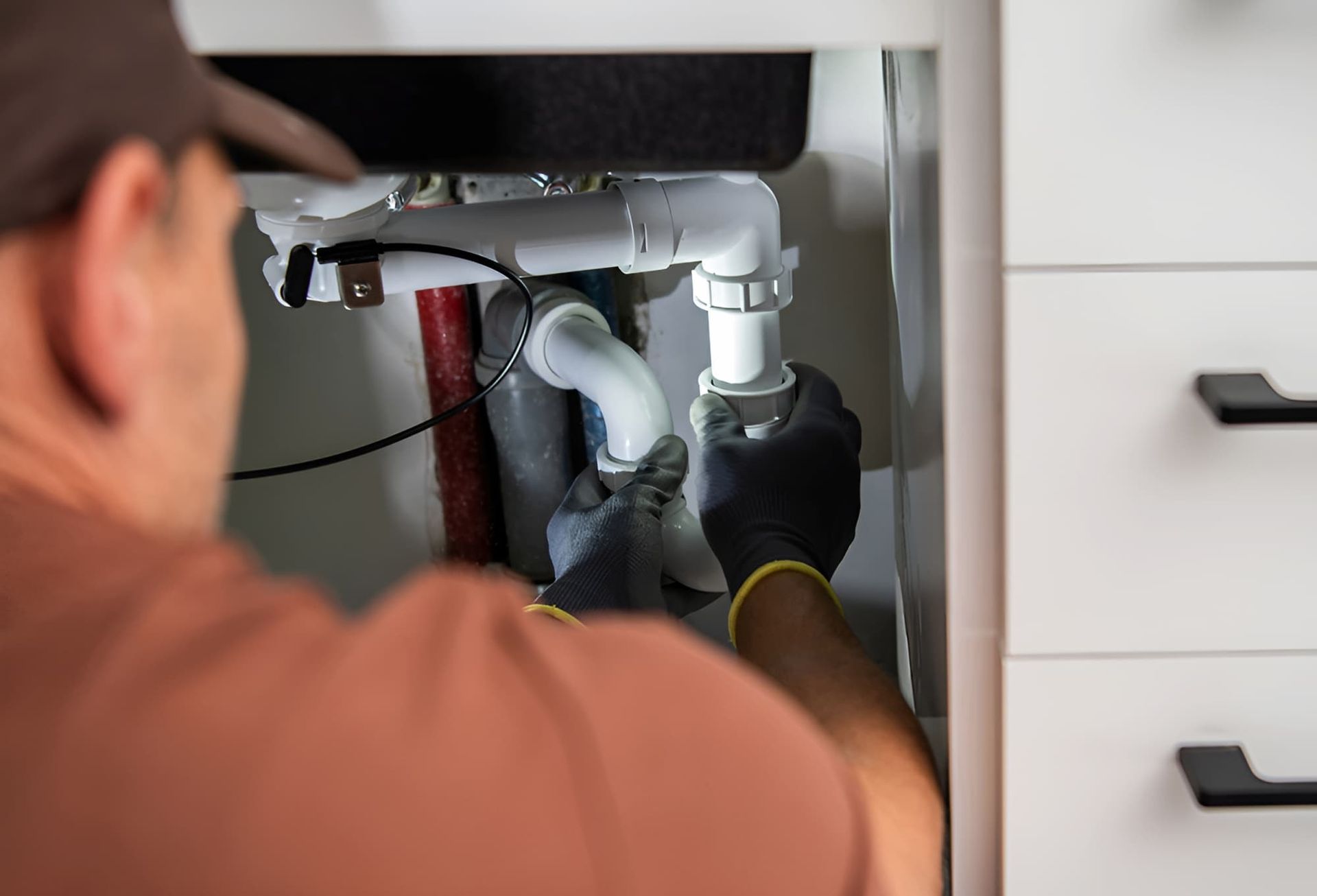 A Man Is Fixing A Sink With A Wrench — GPS Plumbing, Drainage & Gasfitting In Dubbo, NSW