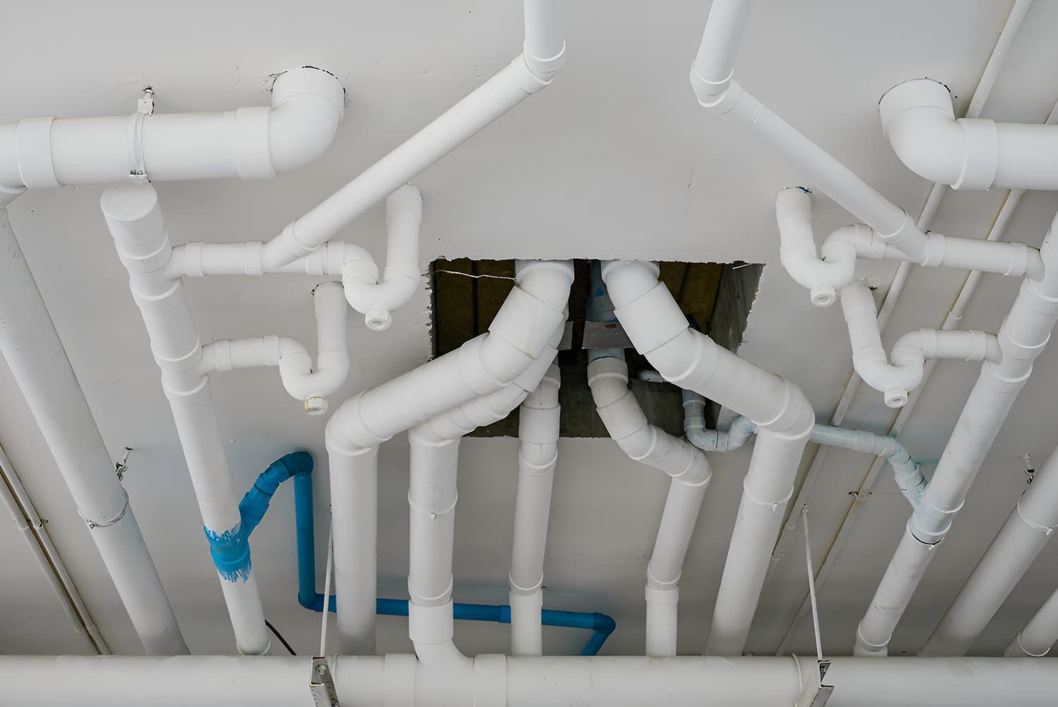 A Bunch Of White Pipes Are Hanging From The Ceiling Of A Building — GPS Plumbing, Drainage & Gasfitting In Dubbo, NSW