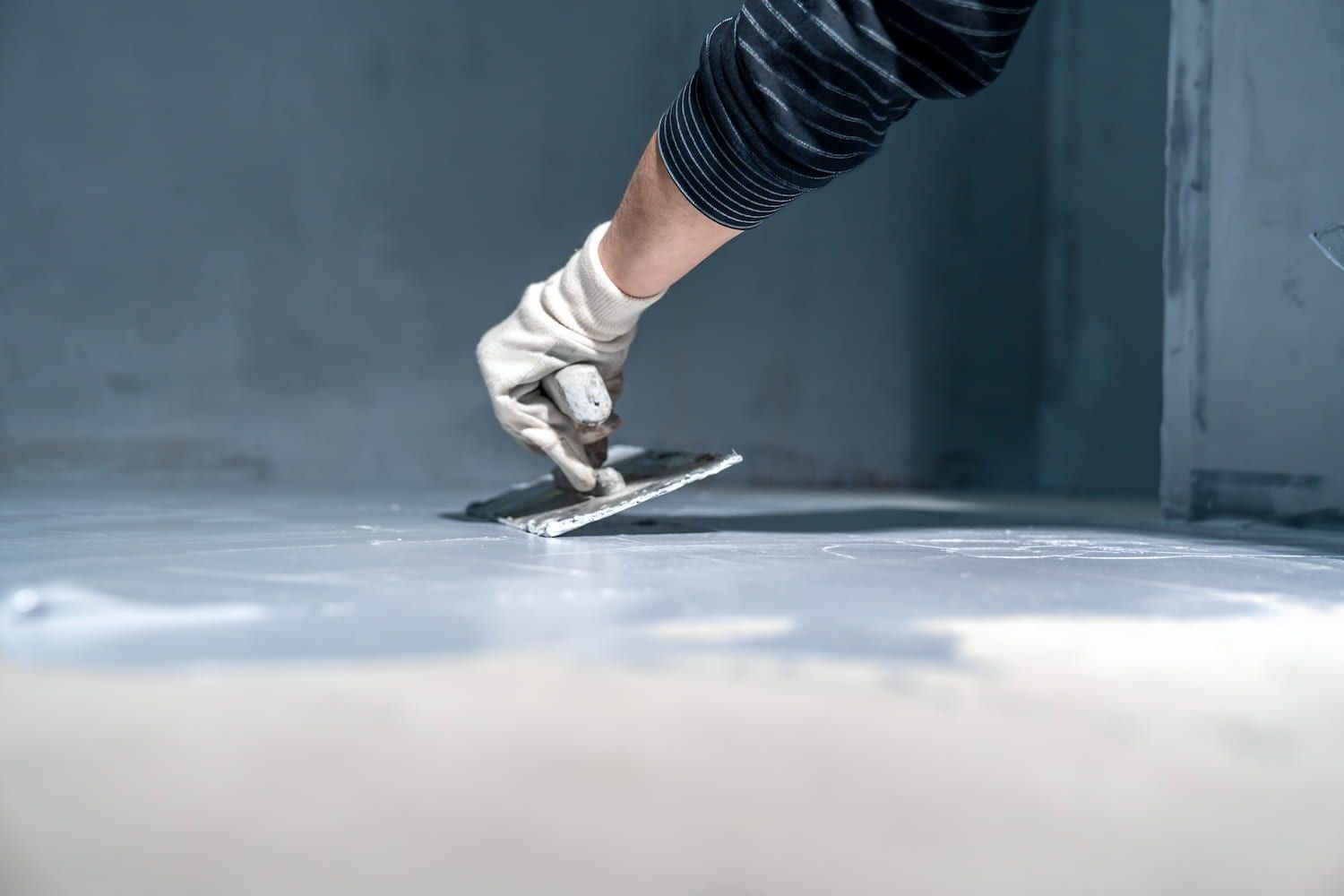 A Person Is Plastering A Floor With A Trowel — GPS Plumbing, Drainage & Gasfitting In Dubbo, NSW