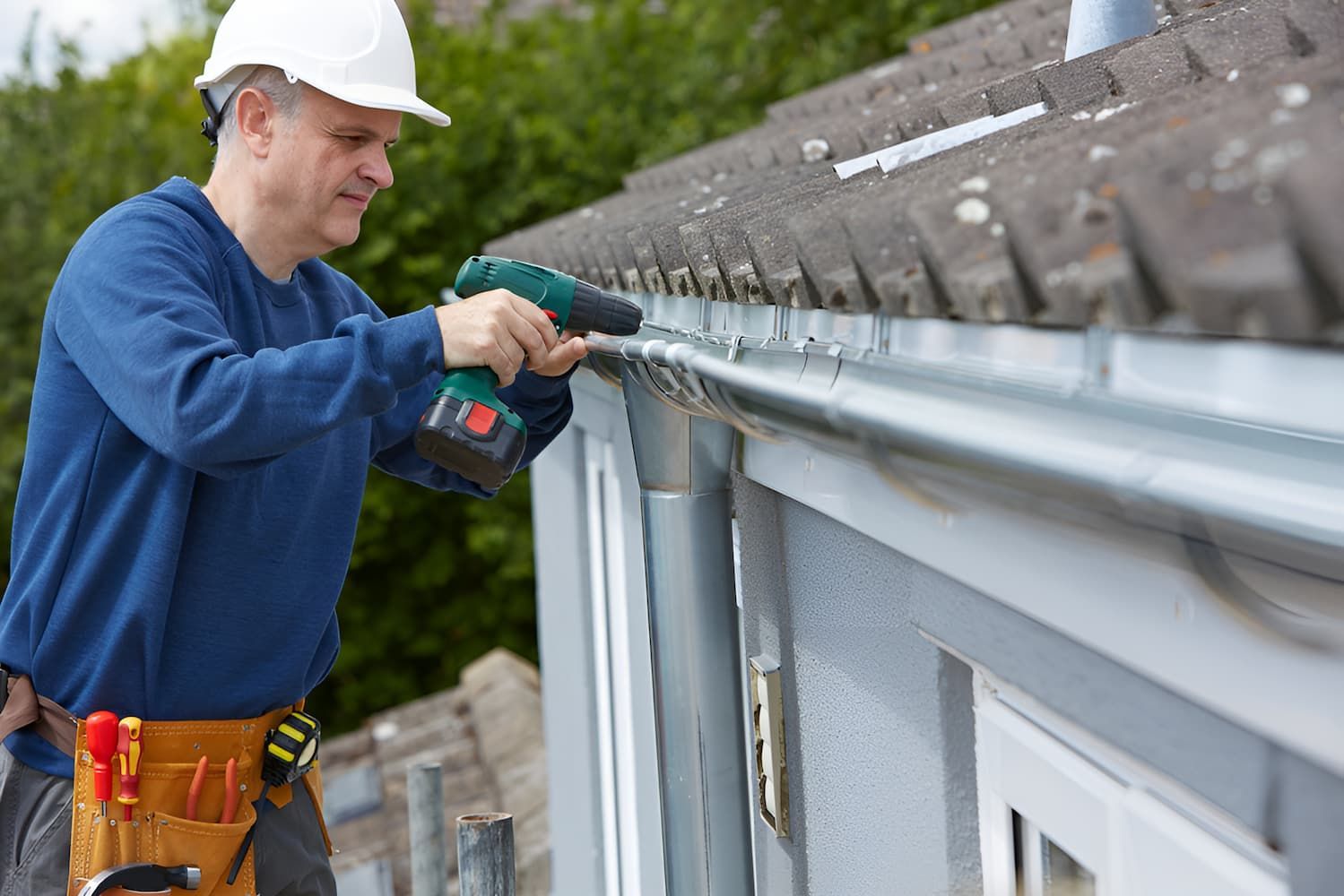 A Man Is Installing A Gutter On The Side Of A House — GPS Plumbing, Drainage & Gasfitting In Dubbo, NSW