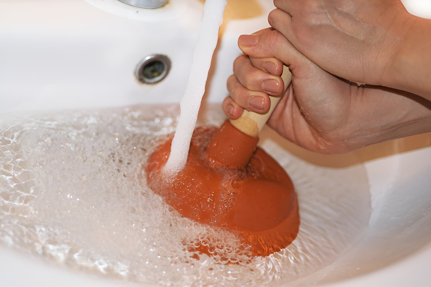 A Person Is Using A Plunger To Unblock A Sink — GPS Plumbing, Drainage & Gasfitting In Dubbo, NSW
