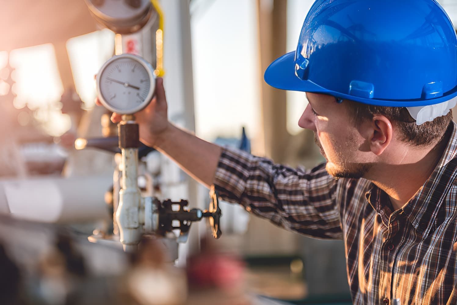 A Man Wearing A Blue Hard Hat Is Holding A Pressure Gauge — GPS Plumbing, Drainage & Gasfitting In Dubbo, NSW