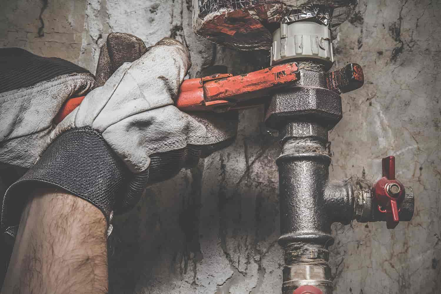 A Person Is Fixing A Pipe With A Wrench — GPS Plumbing, Drainage & Gasfitting In Dubbo, NSW