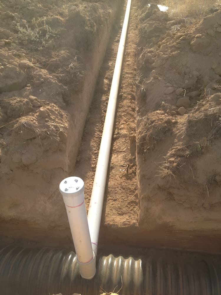 A White Pipe Is Being Installed In The Dirt — GPS Plumbing, Drainage & Gasfitting In Dubbo, NSW