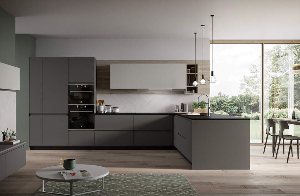 Moderna cucina grigia con isola, forni integrati e ampia finestra con vista sul cortile.