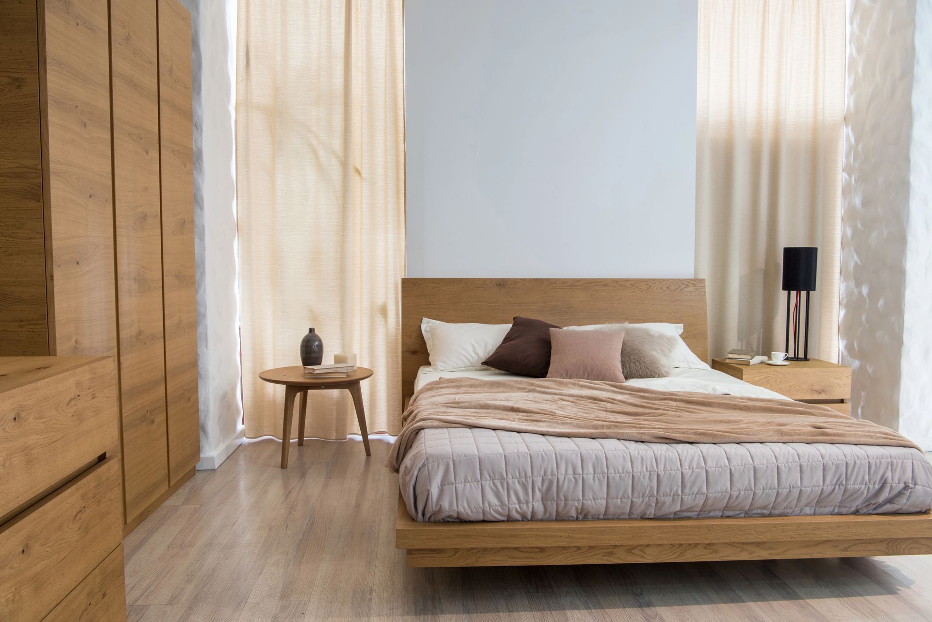 Camera da letto con mobili in legno: letto, comodino, cassettiera. Toni beige e marrone, luce naturale.