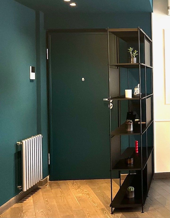 Cucina e soggiorno moderni con mobili bianchi, piano di lavoro nero, divano con cuscini rossi.