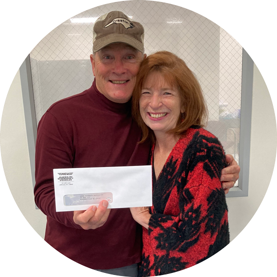 A man and woman are posing for a picture and the woman is holding a check