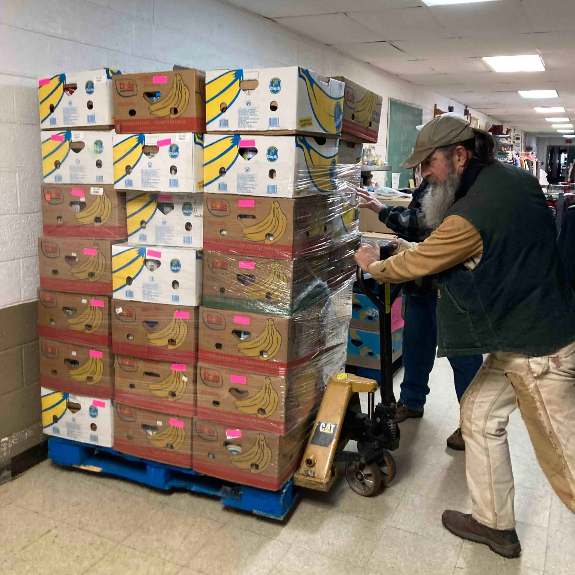 A man is pushing a pallet with banana boxes on it.