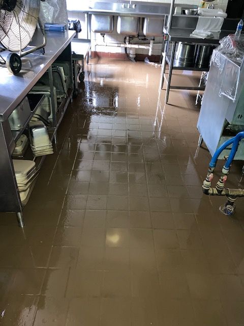 A kitchen with a flooded floor and sinks.