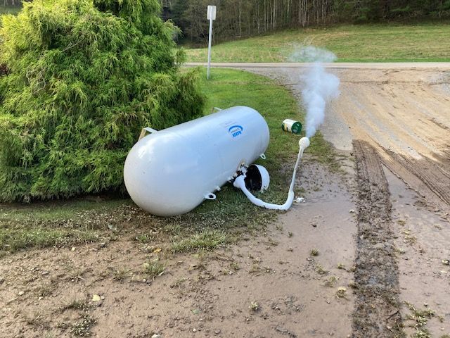 A propane tank is sitting on the side of the road.