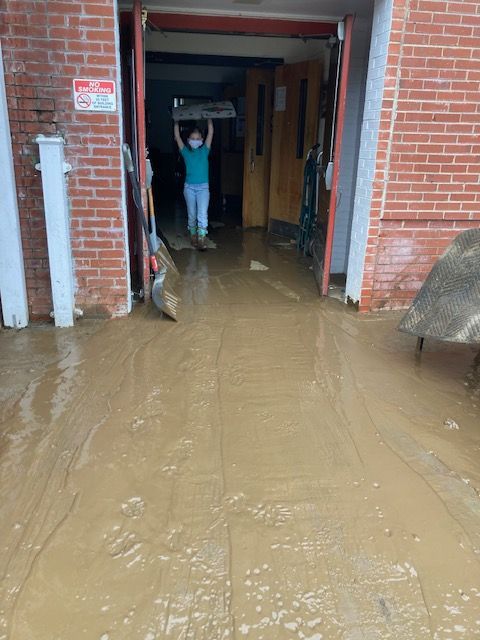 A person is standing in the doorway of a flooded building.