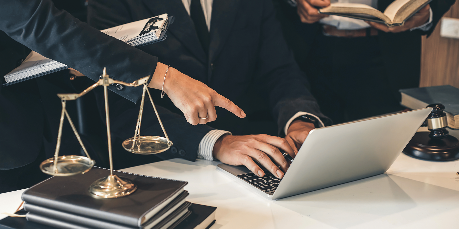 A judge 's gavel is sitting on a wooden table next to two people.