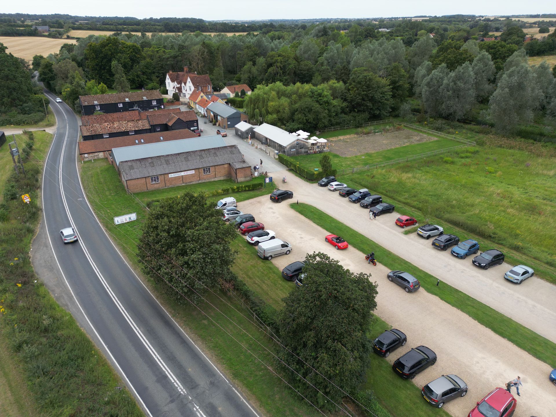 Aerial photo of the shopping complex site called Baythorne Hall, image shows car park with cars and old rustic farm buildings