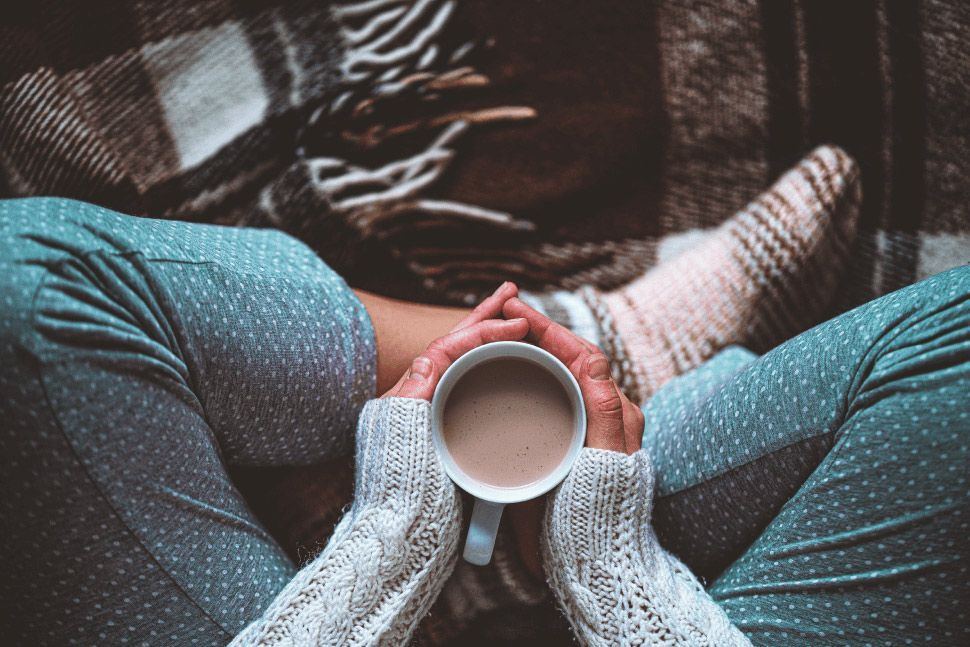 A Person is Sitting on a Couch Holding a Cup of Coffee — Gold Coast Detox and Rehab Services in Gold Coast, QLD