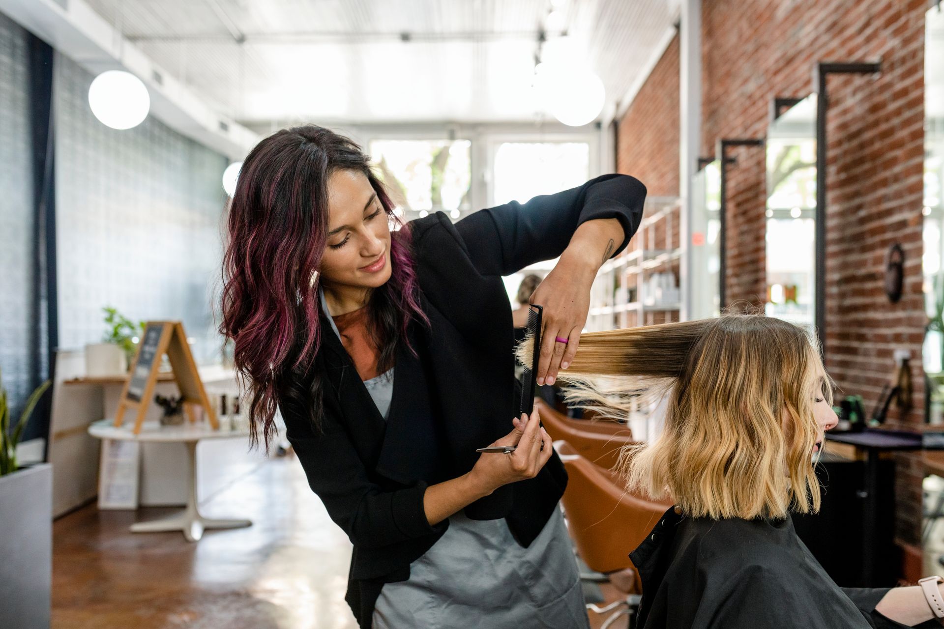 A Woman is Getting Her Hair Cut by a Hairdresser in a Salon — Gold Coast Detox and Rehab Services in Gold Coast, QLD