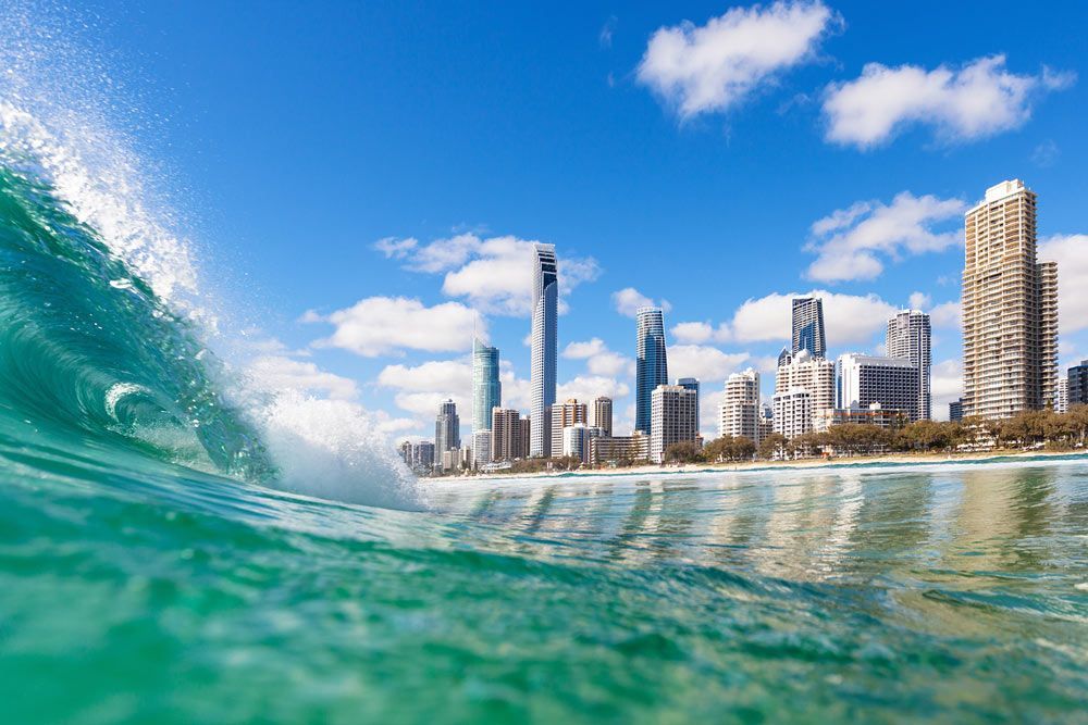 Wave Is Breaking In Front Of A City Skyline — Gold Coast Detox and Rehab Services in Gold Coast, QLD