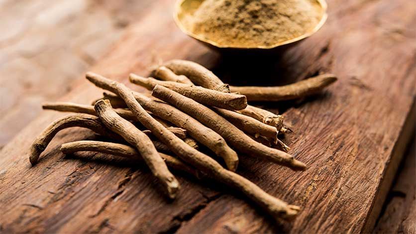A Pile of Ashwagandha Roots Next to a Bowl of Powder on a Wooden Table — Gold Coast Detox and Rehab Services in Gold Coast, QLD