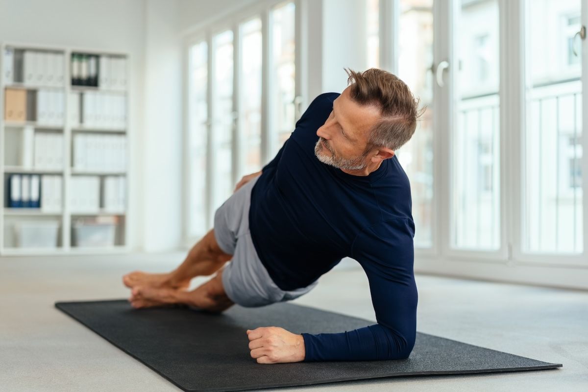 A Man is Doing a Plank on a Yoga Mat in a Living Room — Gold Coast Detox and Rehab Services in Gold Coast, QLD
