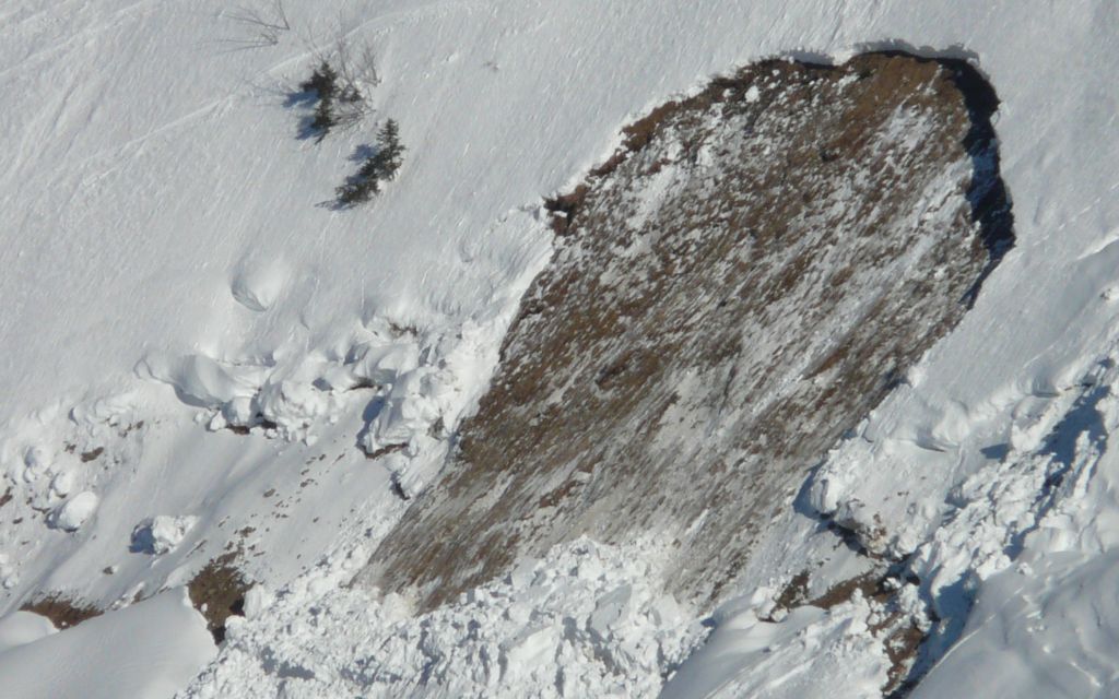 Vista aérea de una ladera nevada con una gran huella de alud visible