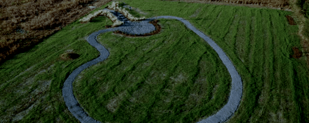 Aerial view of a winding path through a grassy field