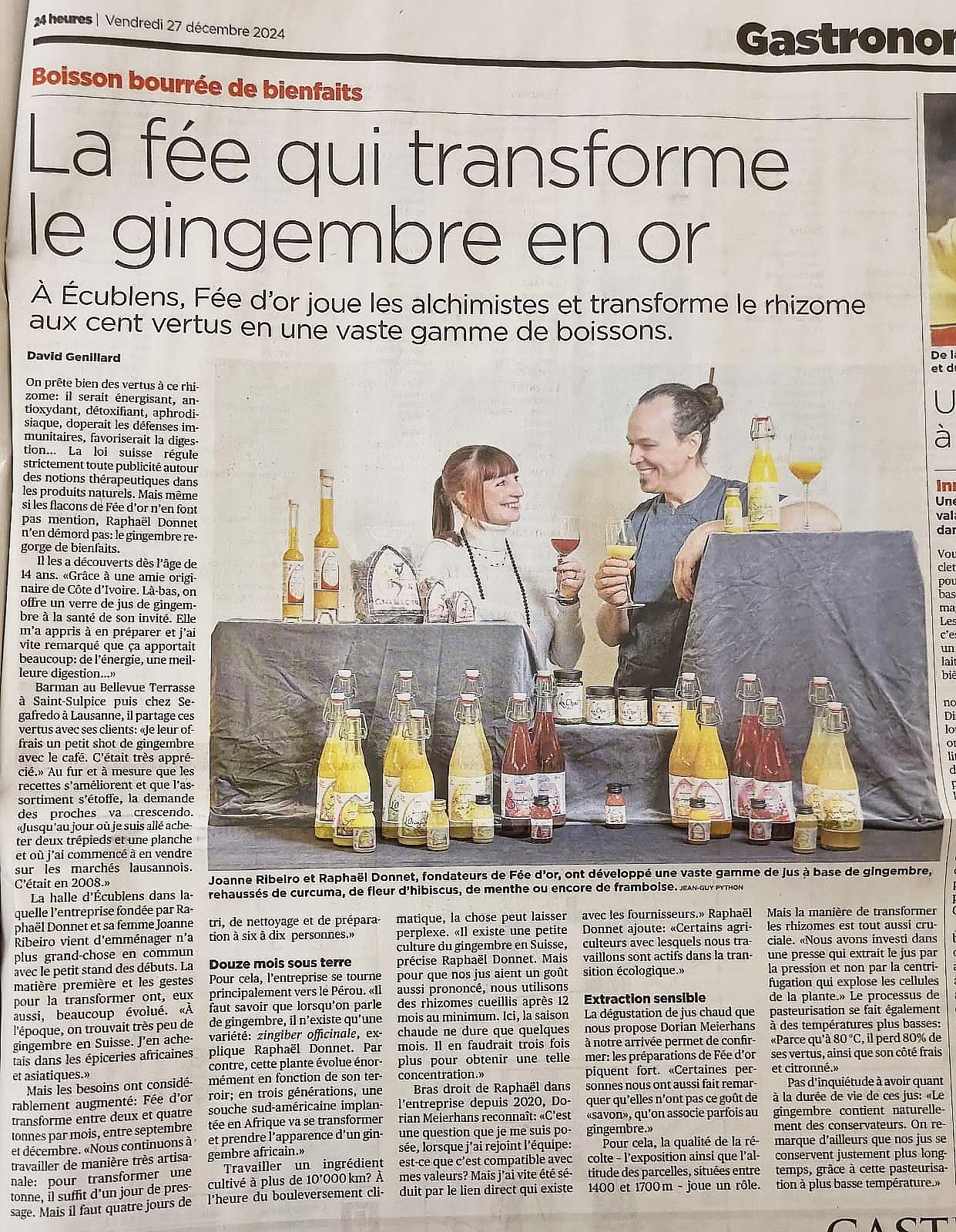 Article de journal avec photo de deux personnes derrière une table présentant des boissons colorées à base de gingembre.
