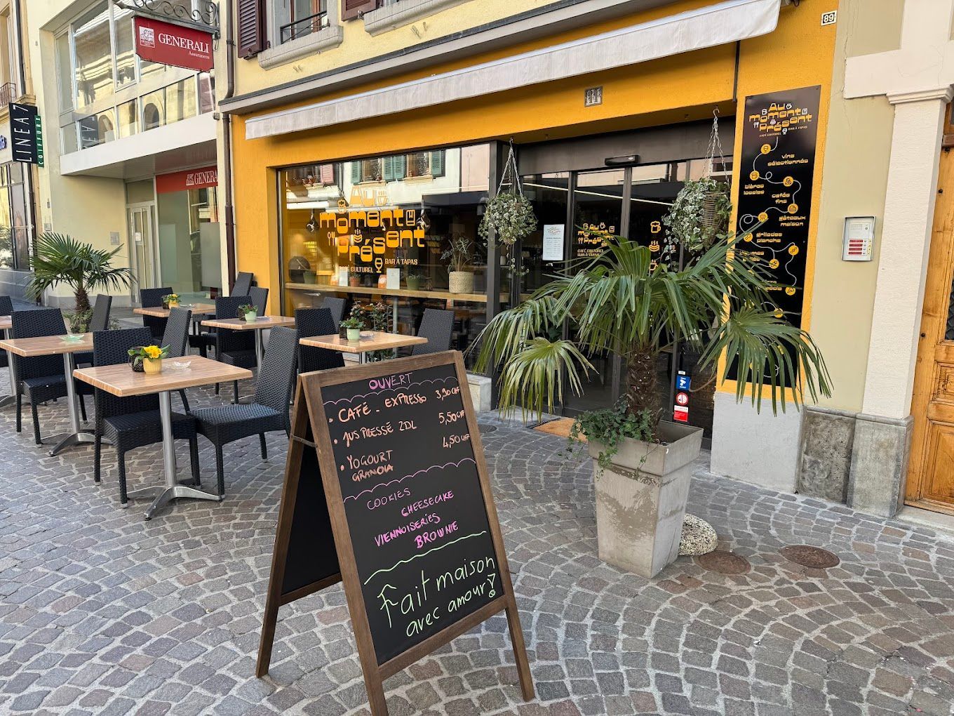 Façade de restaurant avec terrasse et menu affiché sur une rue pavée.