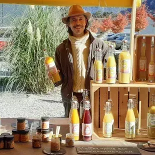 Un homme se tient devant une table tenant une bouteille de jus d'orange.