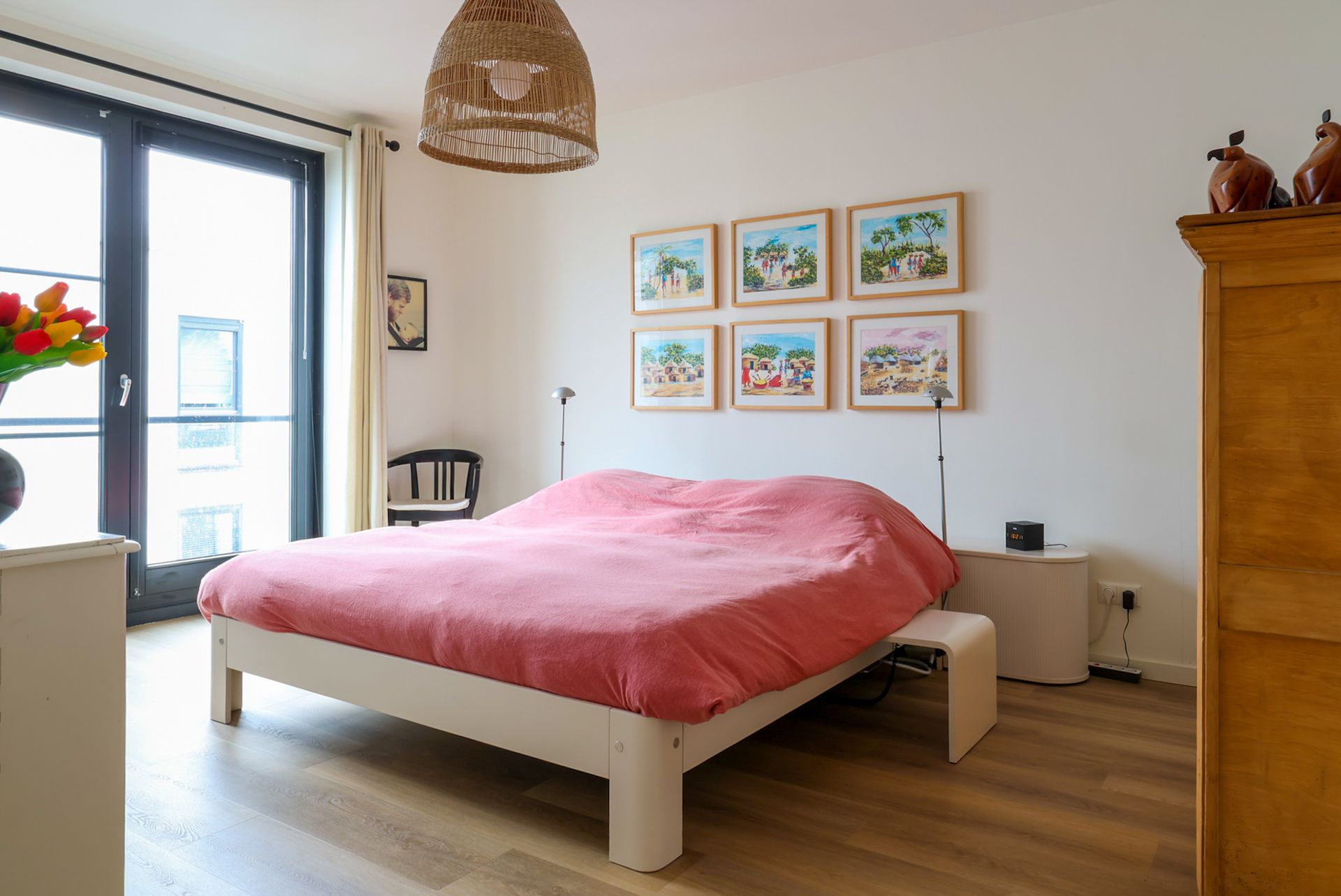 Een moderne woonkamer met maar liefst ruimte voor 3 royale banken. In beige en zwart, en een zwarte sofa, een houten salontafel, een hoogpolig vloerkleed en grote ramen van vloer tot plafond, die toegang geven tot het zeer grote balkon.
