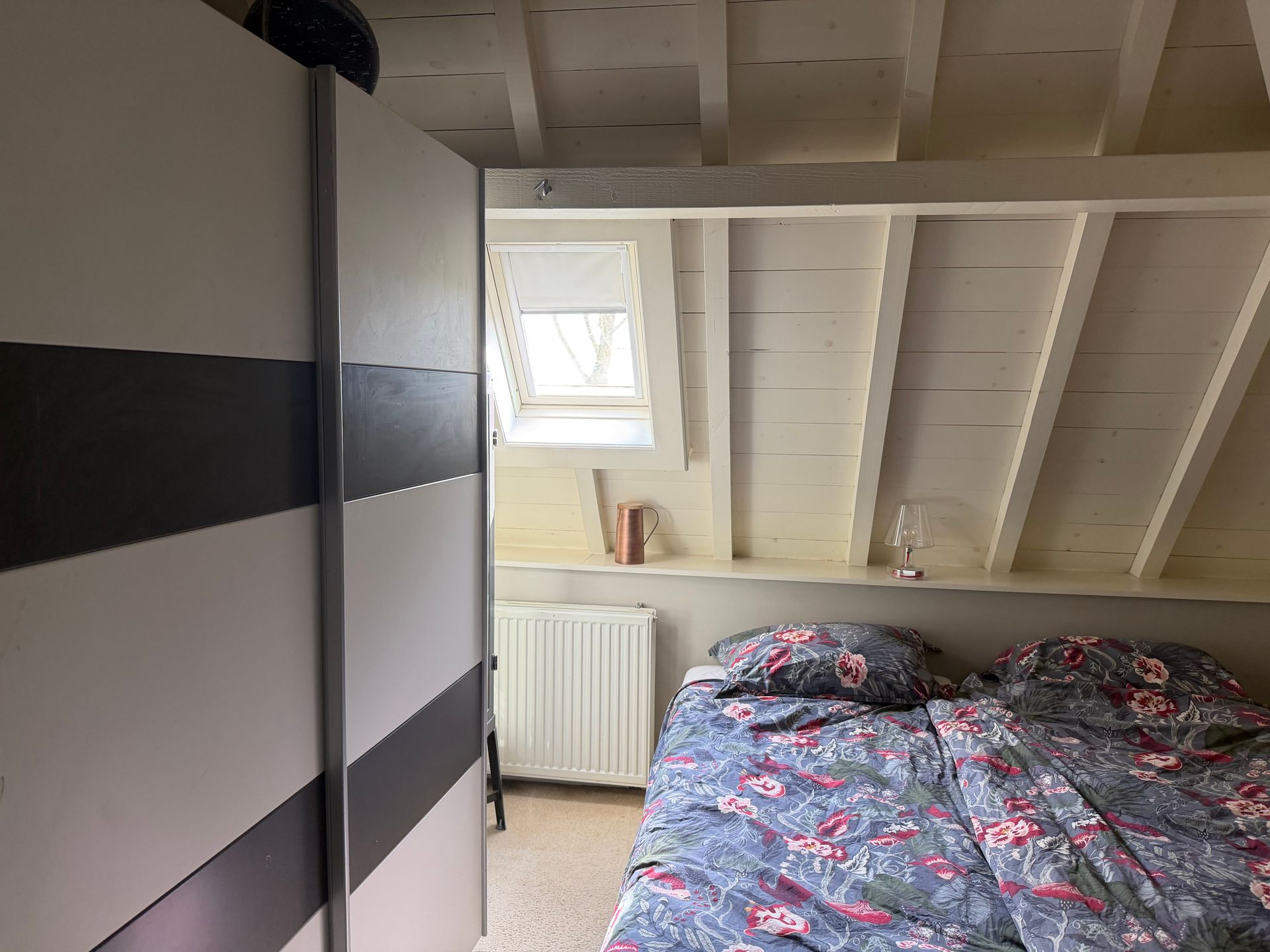 Slaapkamer vooraf gaand aan styling. Raampartijen zijn niet goed zichtbaar, looproutes naar het raam niet vrij. Bed, niet strak opgemaakt.