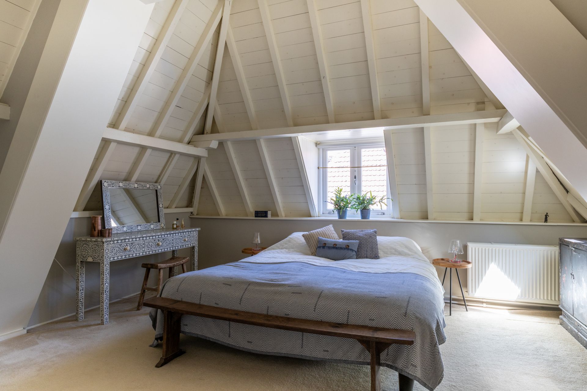 Ruime kamer met een lange houten eettafel, zwarte stoelen, een grote kast en prachtige kamerplanten in een modern penthouse.