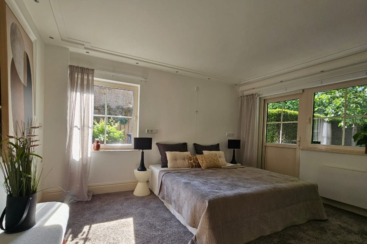 Slaapkamer vooraf gaand aan styling. Raampartijen zijn niet goed zichtbaar, looproutes naar het raam niet vrij. Bed, niet strak opgemaakt.
