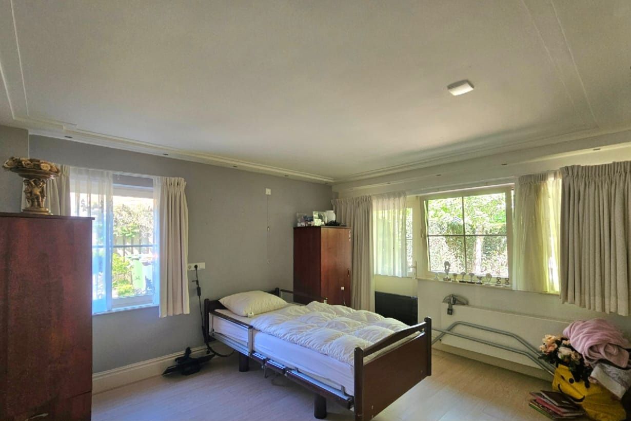 Slaapkamer vooraf gaand aan styling. Raampartijen zijn niet goed zichtbaar, looproutes naar het raam niet vrij. Bed, niet strak opgemaakt.