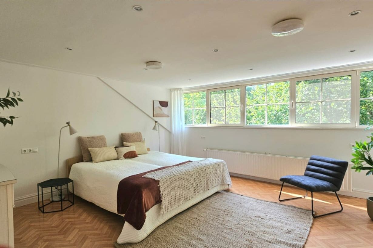 Slaapkamer vooraf gaand aan styling. Raampartijen zijn niet goed zichtbaar, looproutes naar het raam niet vrij. Bed, niet strak opgemaakt.