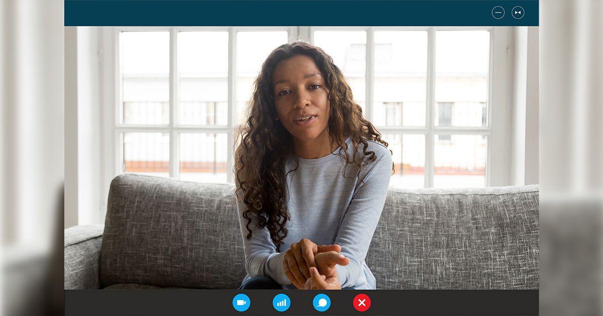 a woman is sitting on a couch in a video call