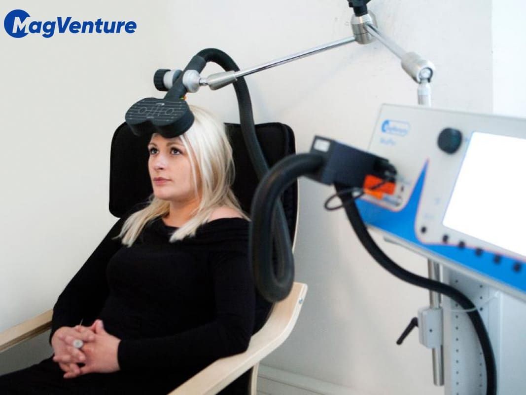 a woman is sitting in front of a Magventure TMS device