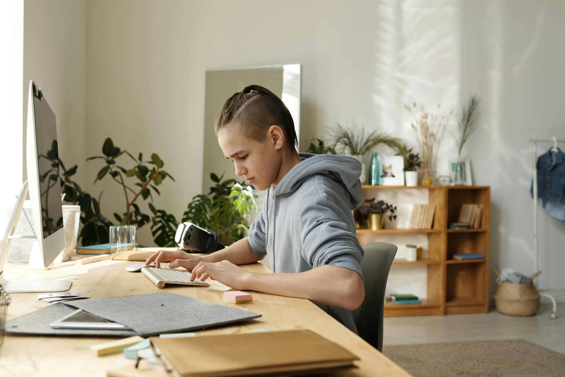 A young man is sitting at a desk in front of a computer.