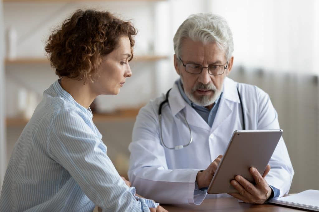 a doctor and patient are looking at a tablet together
