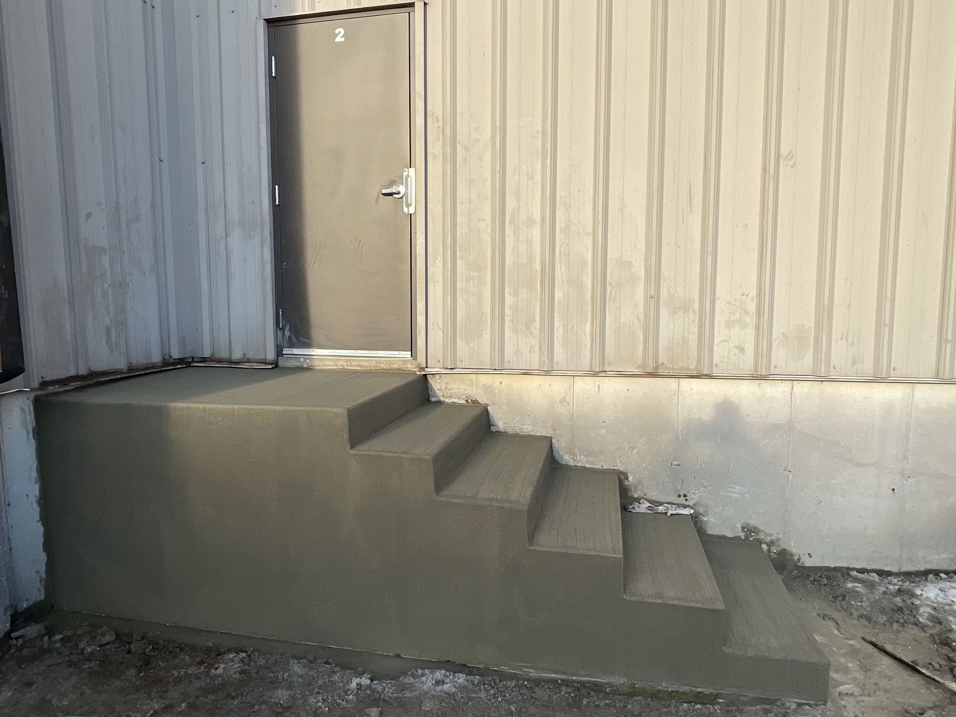A set of concrete stairs leading up to a door on the side of a building.