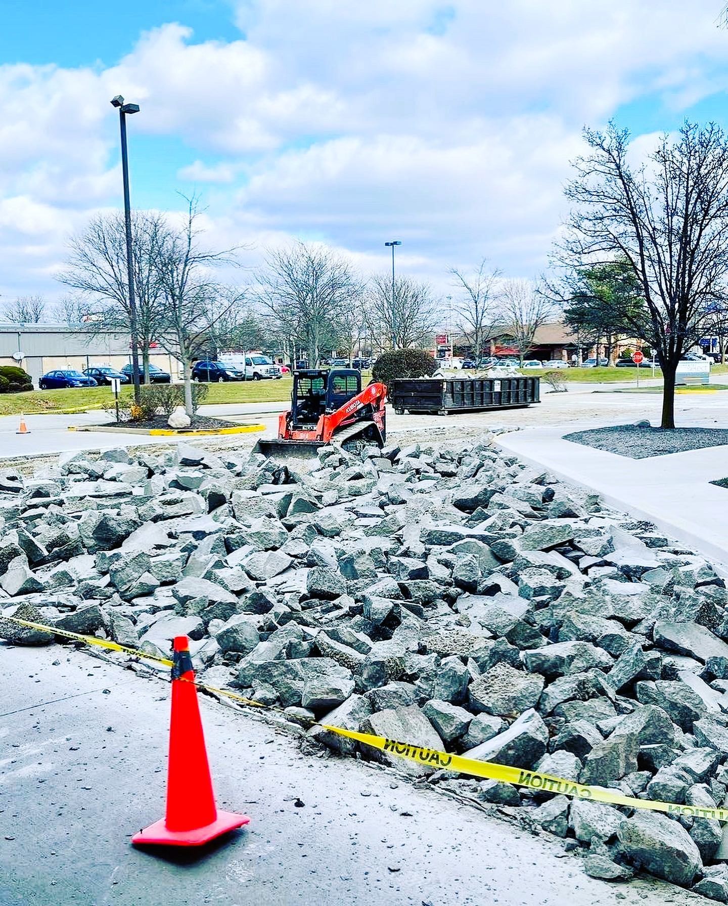 A red cone is sitting on the side of a road next to a pile of rocks.