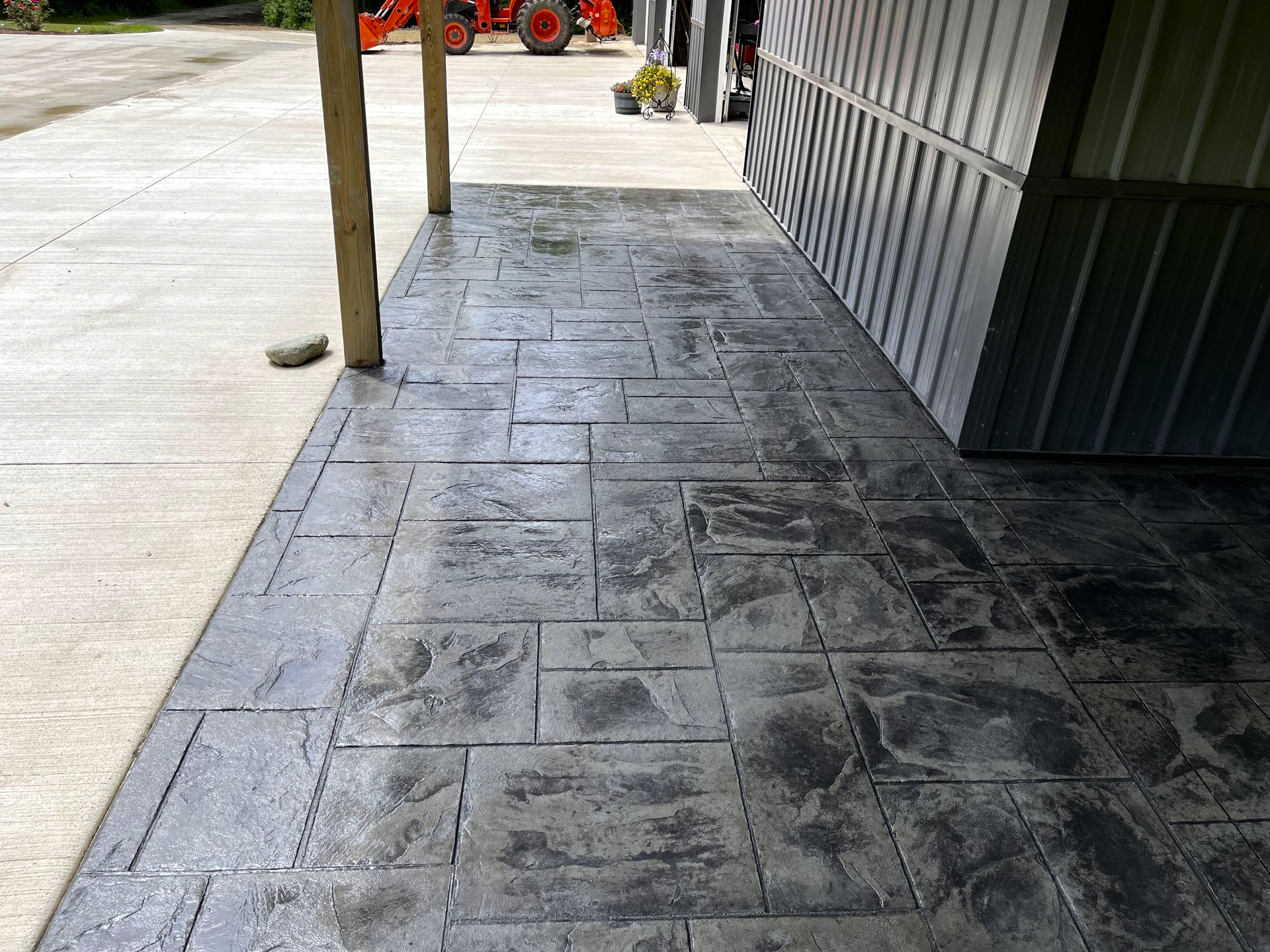 A concrete walkway leading to a building with a tractor in the background.