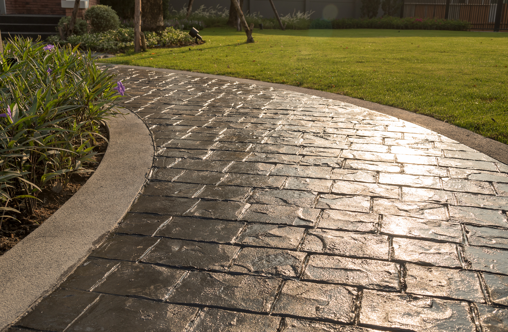 A brick walkway leading to a lush green field.