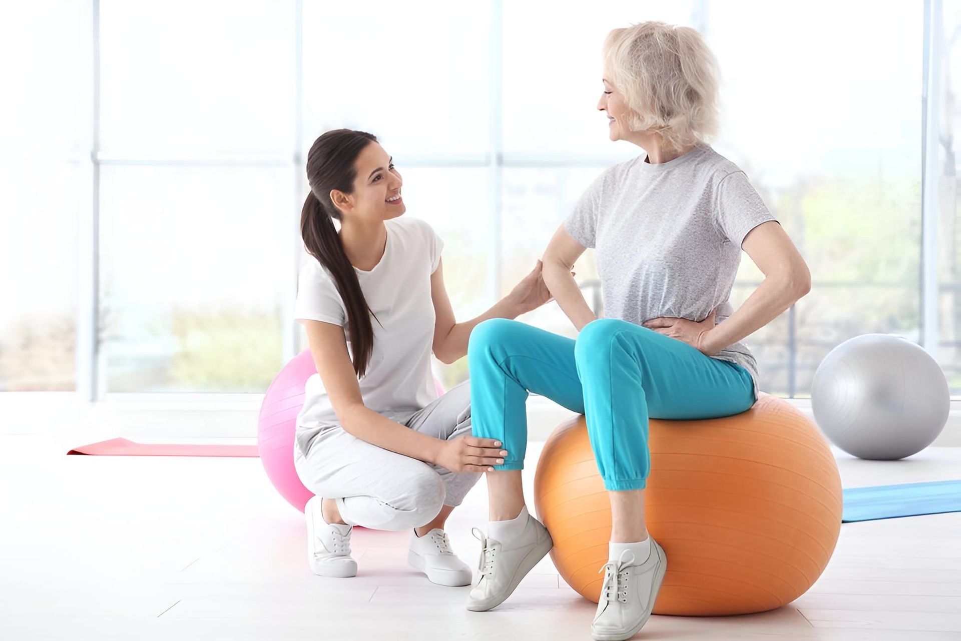 A Woman is Sitting on an Orange Exercise Ball While a Nurse Helps Her — Active Lifestyle Supports In Shellharbour, NSW
