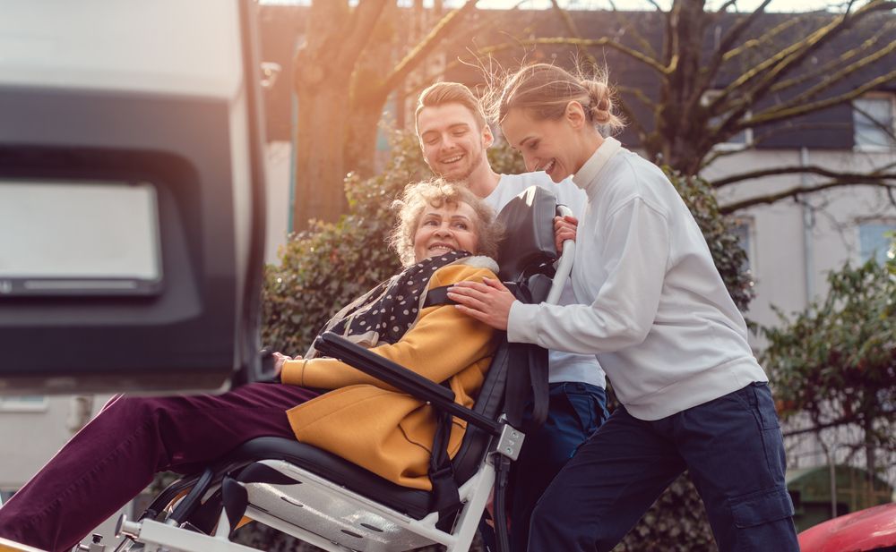 Two Care Workers Assisting a Disabled Woman in Wheelchair for Transport — Active Lifestyle Supports In Tullimbar, NSW
